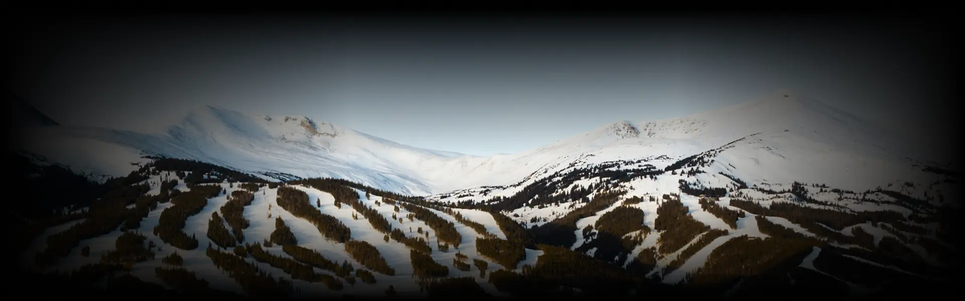 Snow-covered slopes and alpine trees stretch across Copper Mountain under a clear sky—highlighting the breathtaking winter terrain along the Denver to Copper Mountain route.