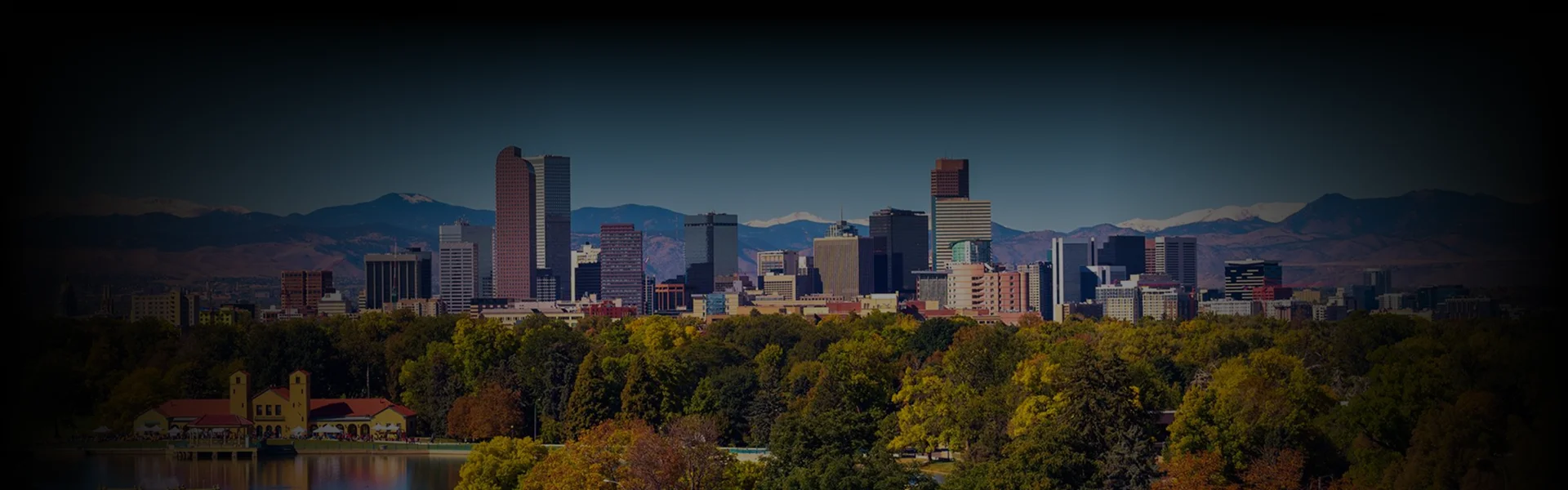 Skyline view of Denver with Colorado Car Service text overlay, framed by lush trees and distant Rockies in soft daylight.
